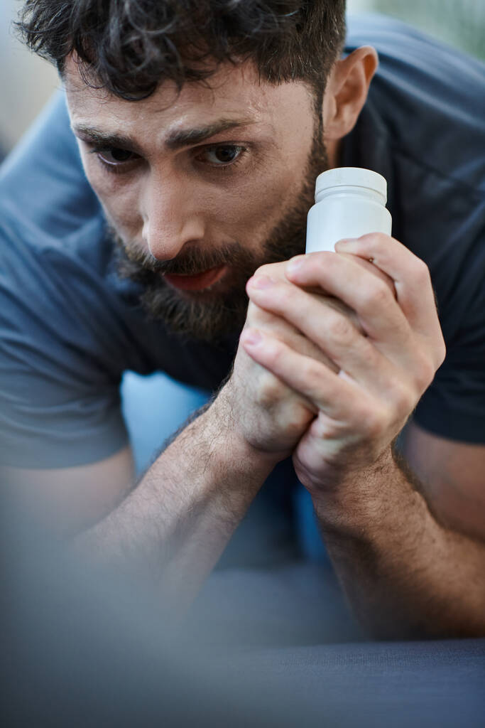 Verzweifelter Mann mit Tabletten in der Hand während depressiver Episode mit Selbstverletzungen, Bewusstsein für psychische Gesundheit - Foto, Bild
