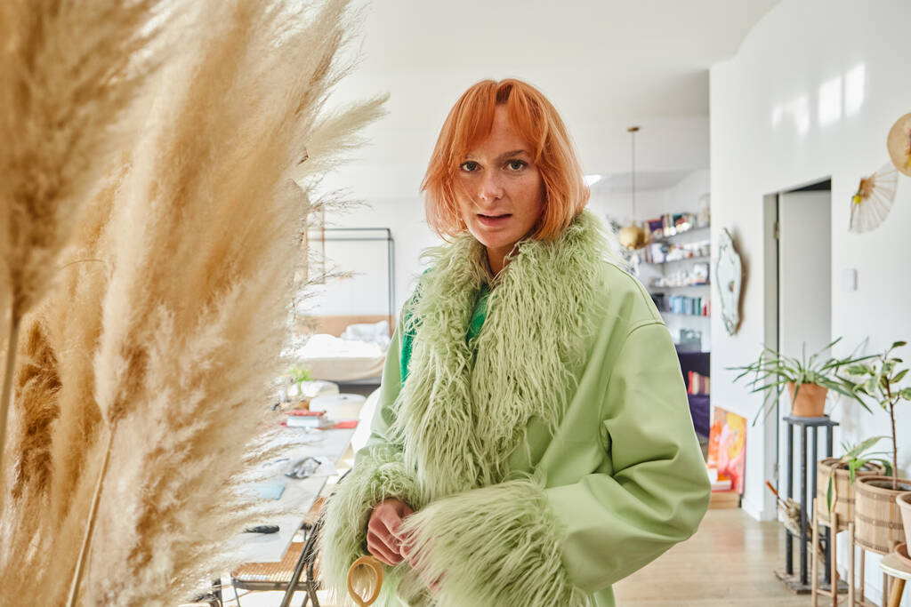 Frau in stylischer Oberbekleidung blickt in Wohnung mit modernem Interieur in Wien in die Kamera - Foto, Bild