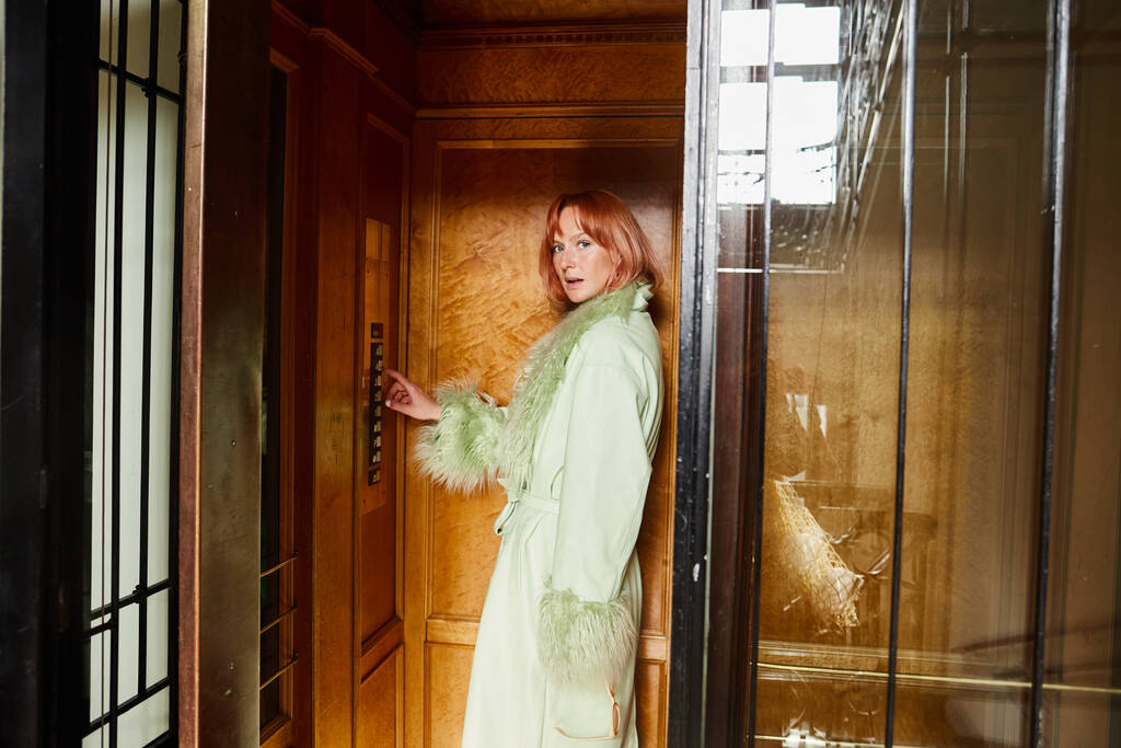 donna alla moda guardando la fotocamera da ascensore vintage in palazzo residenza a Vienna, Austria - Foto, immagini