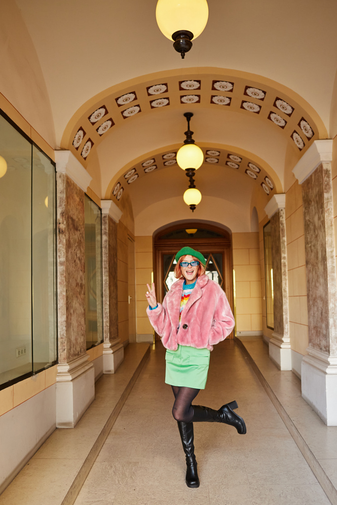 возбужденная женщина в модном наряде и солнцезащитных очках, показывающих знак победы в здании Вены, Австрия - Фото, изображение