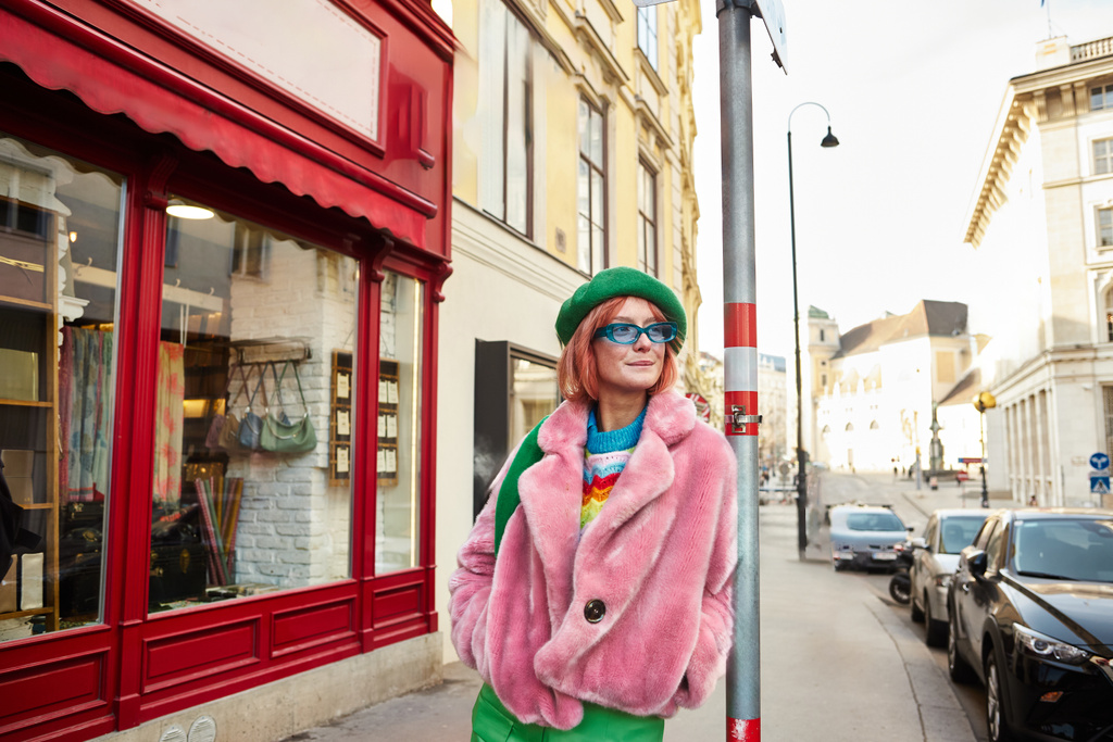 mujer con estilo en chaqueta de piel sintética y gafas de sol mirando hacia otro lado en la calle urbana de Viena, Austria - Foto, Imagen