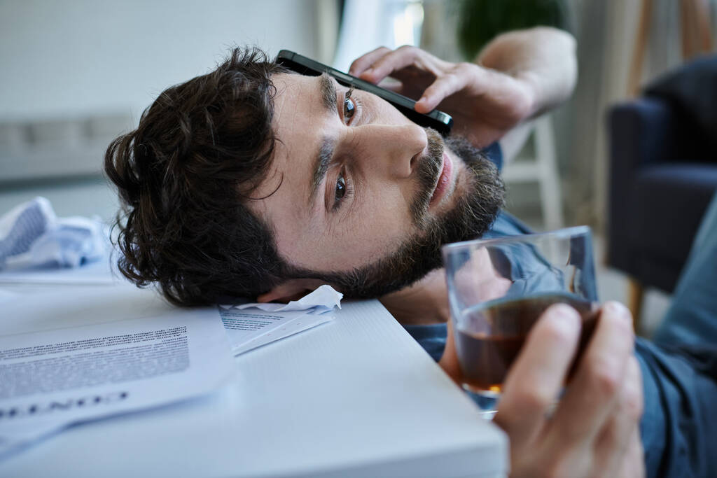 gefrustreerde man praten met smartphone met alcohol in de handen tijdens de inzinking, geestelijke gezondheid bewustzijn - Foto, afbeelding