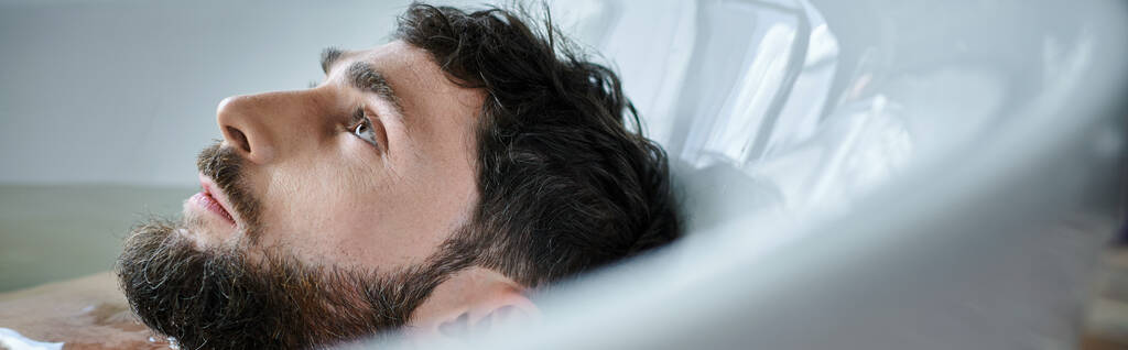 hombre frustrado deprimido con barba acostado en la bañera durante la ruptura, conciencia de salud mental - Foto, Imagen