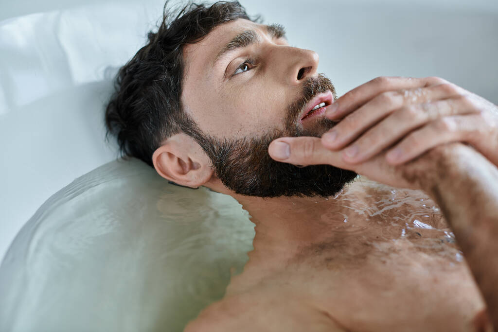 przygnębiony człowiek z urazem brodą leżący w wannie podczas załamania, świadomość zdrowia psychicznego - Zdjęcie, obraz