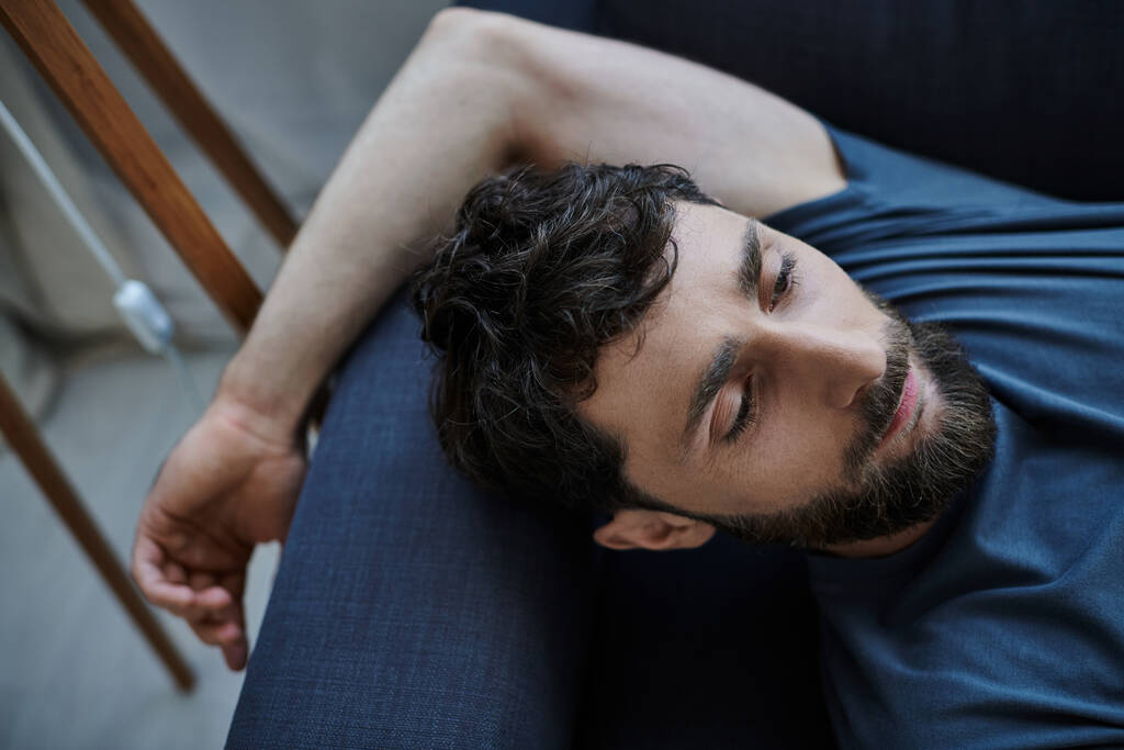 depresivní úzkostlivý muž s vousy v ležérním oblečení ležící na pohovce při duševním zhroucení, vědomí - Fotografie, Obrázek