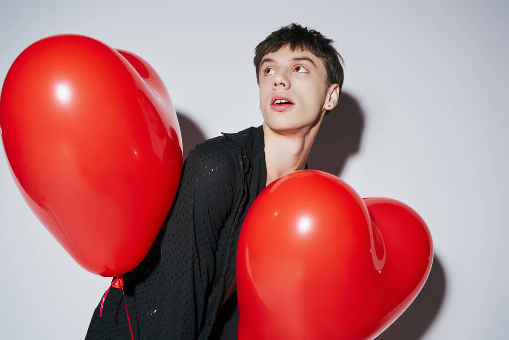 Siyah gömlekli romantik adam elinde kırmızı kalp şeklinde balonlar tutuyordu gri arka planda, Sevgililer Günü - Fotoğraf, Görsel
