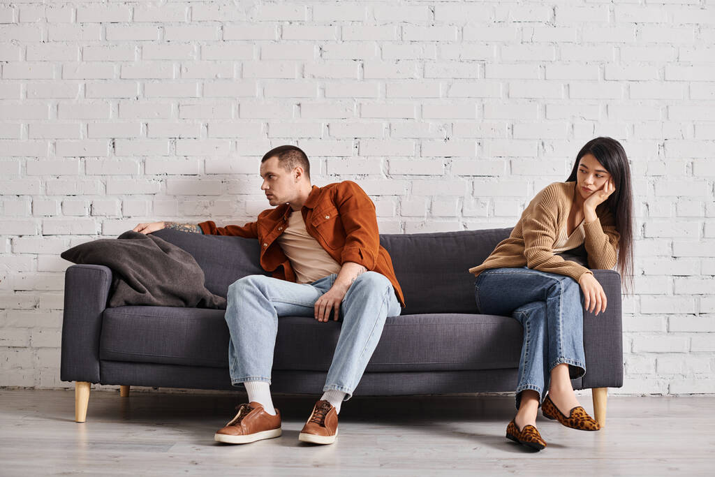 jeune couple interracial avec détresse émotionnelle assis sur le canapé dans le salon, concept de divorce - Photo, image