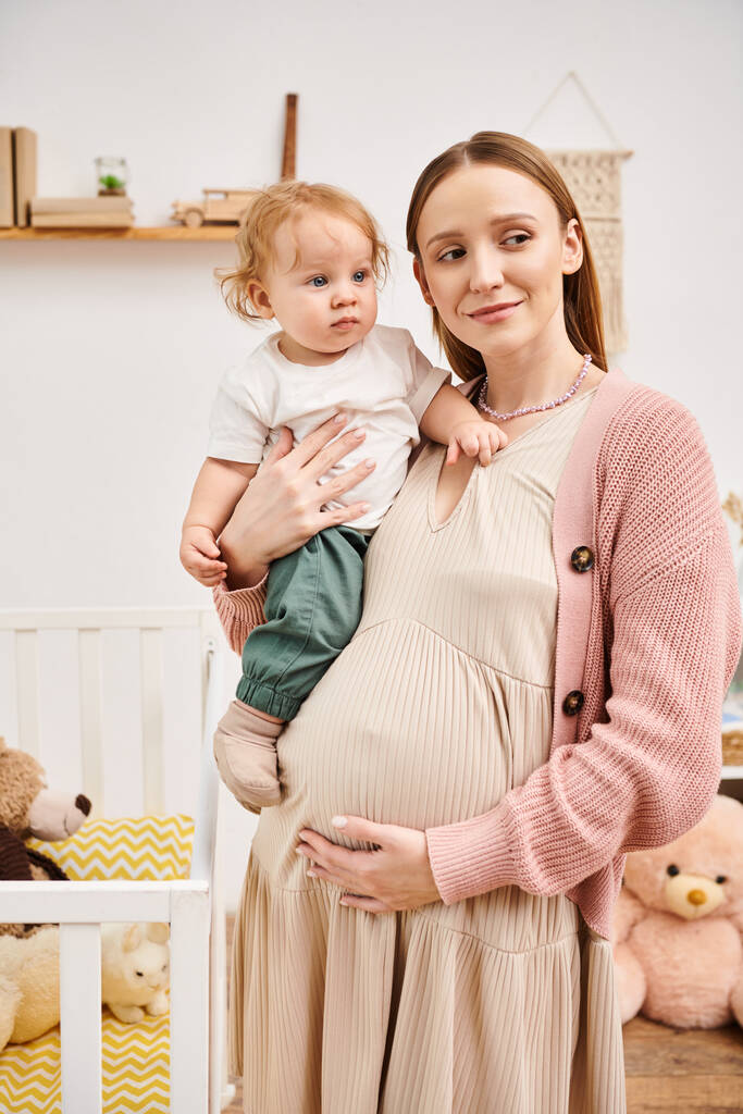 tyytyväinen nuori raskaana oleva nainen seisoo lapsi poika lastenhuoneessa kotona, onnellinen äitiys - Valokuva, kuva