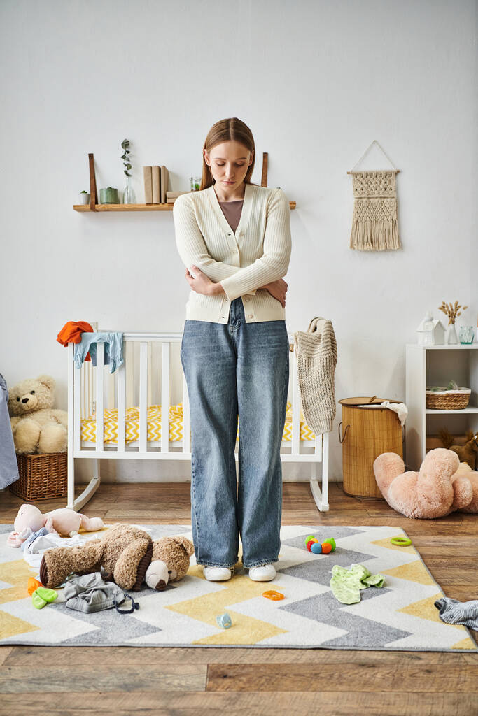 истощенная и безнадежная женщина с мягкой игрушкой, стоящая в детской комнате дома, разбитое сердце - Фото, изображение