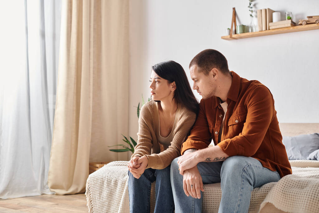 giovane coppia multietnica frustrato seduto e parlando sul letto a casa, difficoltà di relazione - Foto, immagini