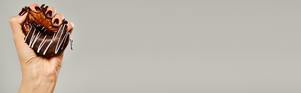 femme inconnue avec vernis à ongles serrant beignet doux avec cerise brune sur fond gris, bannière - Photo, image