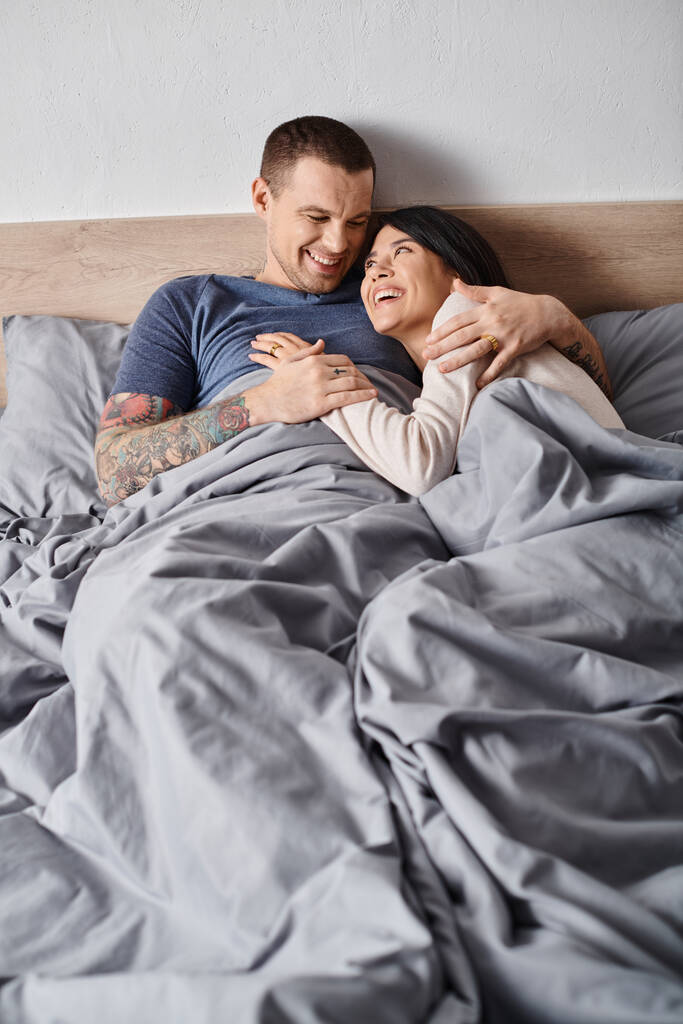 junges multiethnisches Paar, das sich im heimischen Schlafzimmer umarmt und lacht, Vertrauen und Verständnis - Foto, Bild