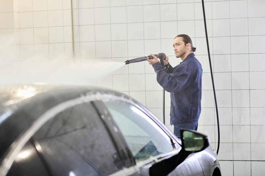 przystojny ciężko pracujący żołnierz w niebieskim mundurze z zebranym samochodem do mycia włosów z wężem - Zdjęcie, obraz