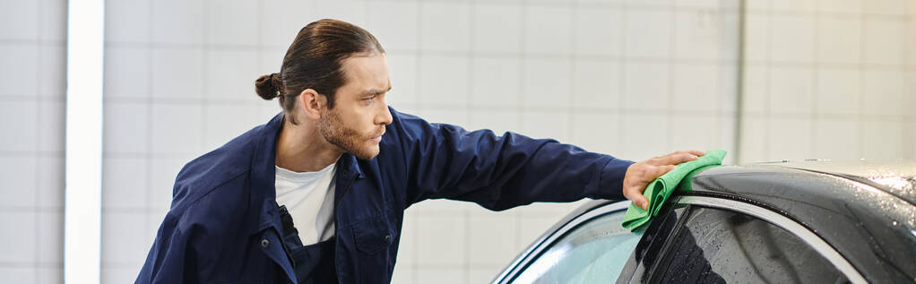 good looking professional worker with collected hair in uniform cleaning black modern car, banner - Photo, Image