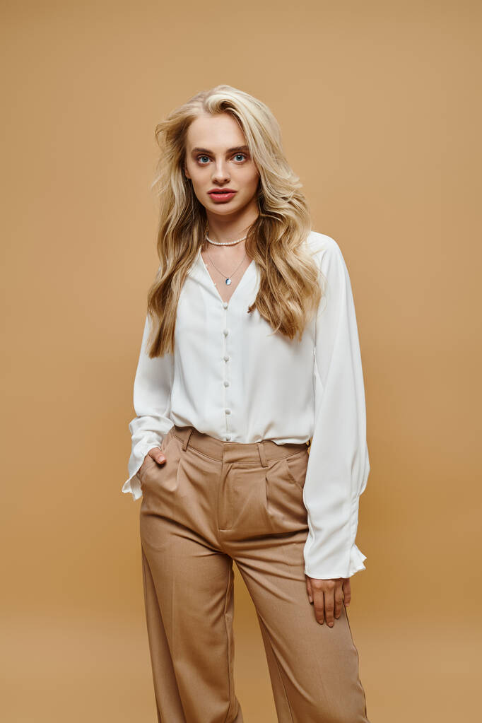 confident blonde woman trendy clothes posing with hand in pocket on beige, old money style fashion - Photo, Image
