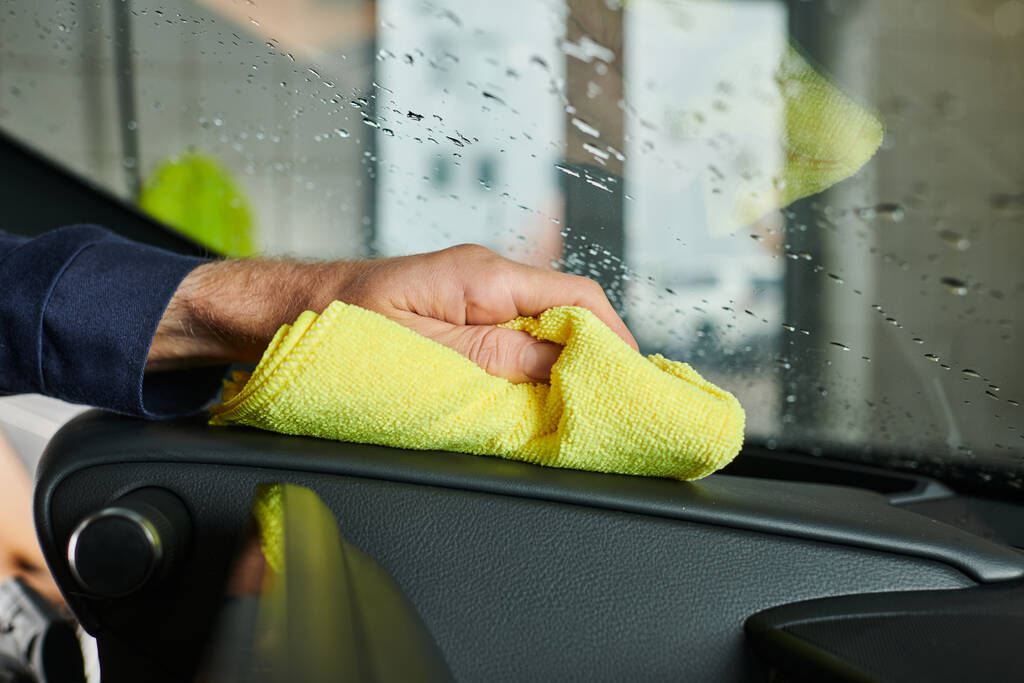 Ausgeschnittene Ansicht von engagierten Servicekräften in Uniform, die aufmerksam das Handschuhfach des Autos reinigen - Foto, Bild