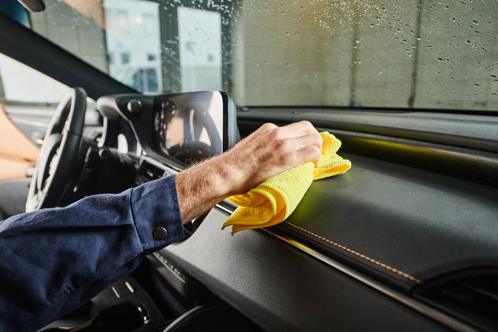 cropped view of dedicated specialist in blue uniform cleaning glove compartment in car with rag - Photo, Image