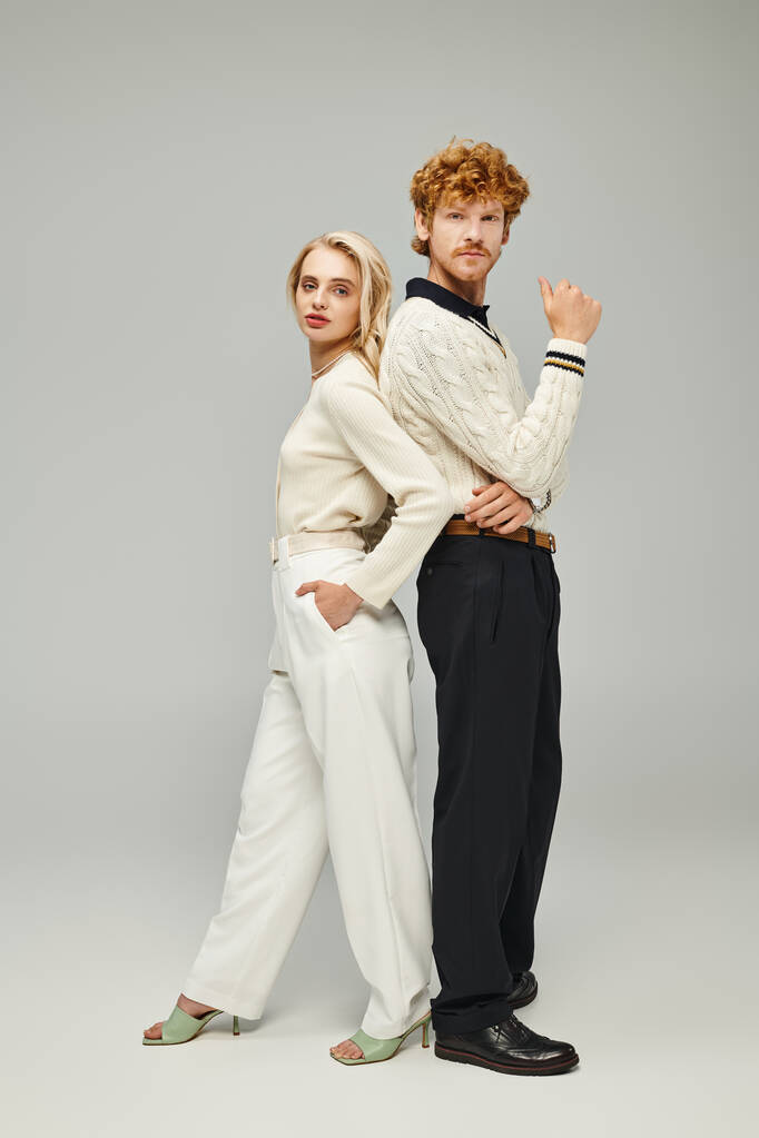 jeune couple en tenue décontractée à la mode posant dos à dos sur gris, mode intemporelle, pleine longueur - Photo, image
