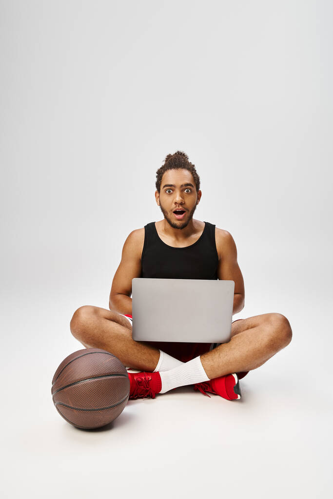 шокований афроамериканський чоловік у спортивному одязі сидить з ноутбуком і дивиться на камеру, онлайн ставки - Фото, зображення