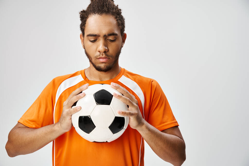 przystojny atletyczny Afroamerykanin człowiek w wygodne odzież sportowa patrząc na piłkę nożną w jego rękach - Zdjęcie, obraz