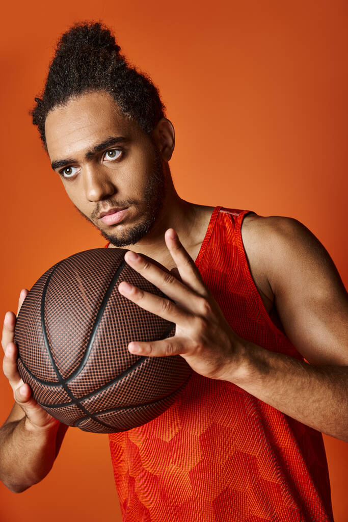 appealing athletic african american sportsman holding basketball on vibrant orange background - Photo, Image