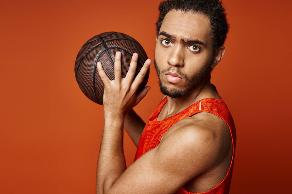バスケットボールでポーズし,カメラを見ている活気に満ちたスポーツ服のハンサムなアフリカ系アメリカ人男性 - 写真・画像