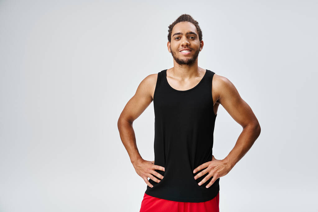 εύθυμος αθλητικός Αφροαμερικάνος με αθλητικά ρούχα με μπράτσα, με χαμόγελο χαρούμενα στην κάμερα, λάβαρο - Φωτογραφία, εικόνα