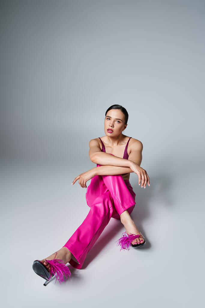 Mulher morena confiante na moda top vermelho e rosa calças e sapatos, sentado cruzando as pernas - Foto, Imagem