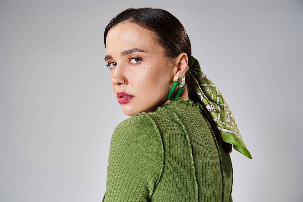 Yeşil moda giyinmiş güzel bir kadının portresi. Gri omuzlara bakıyor. - Fotoğraf, Görsel