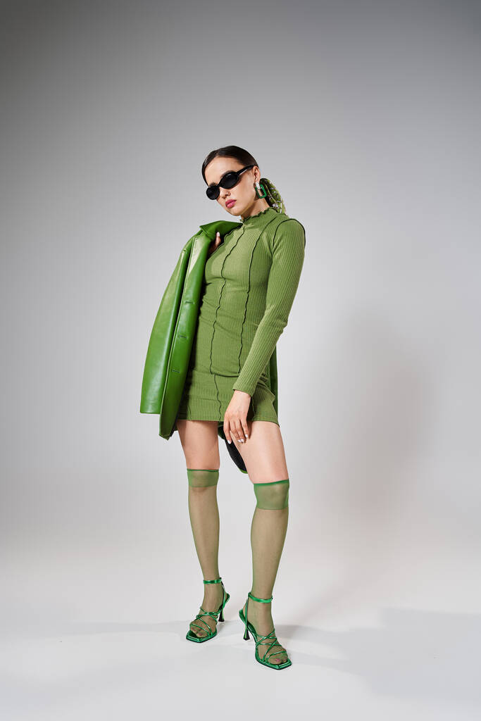 Fabelhaftes Mädchen in grünem Minikleid, Lederjacke, Kniestrümpfen und Schuhen, Hände am Oberschenkel - Foto, Bild