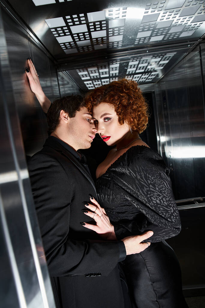 sexy lindo casal em chique vestido preto e terno abraçando no elevador e olhando para a câmera - Foto, Imagem