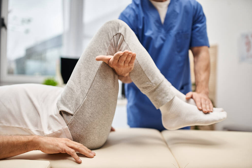 vista recortada del médico trabajador en bata azul estirando a su paciente maduro en la sala de hospital - Foto, imagen