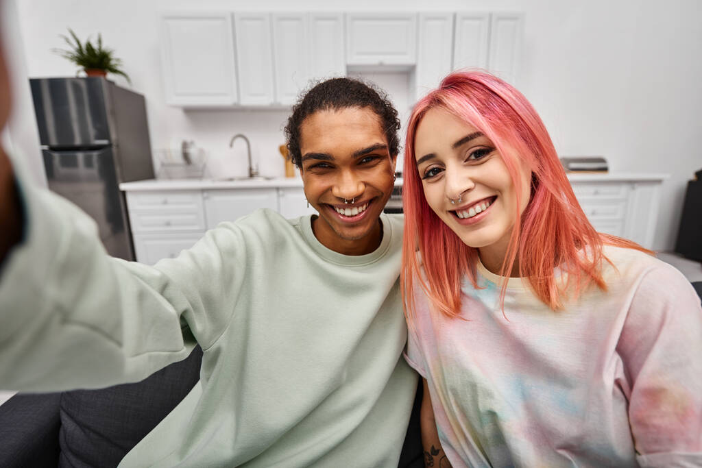 freudig attraktives multikulturelles Paar in lässiger Kleidung, das Selfies macht und in die Kamera lächelt - Foto, Bild