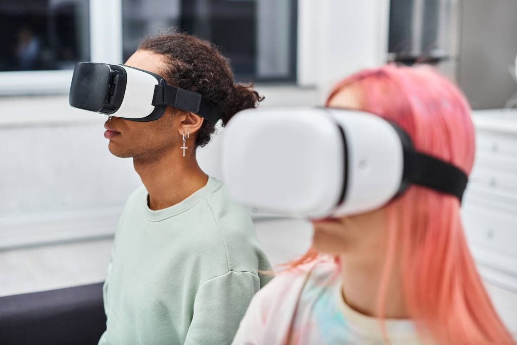 se centran en el hombre afroamericano junto a la novia de pelo rosa borrosa con auriculares de realidad virtual - Foto, Imagen