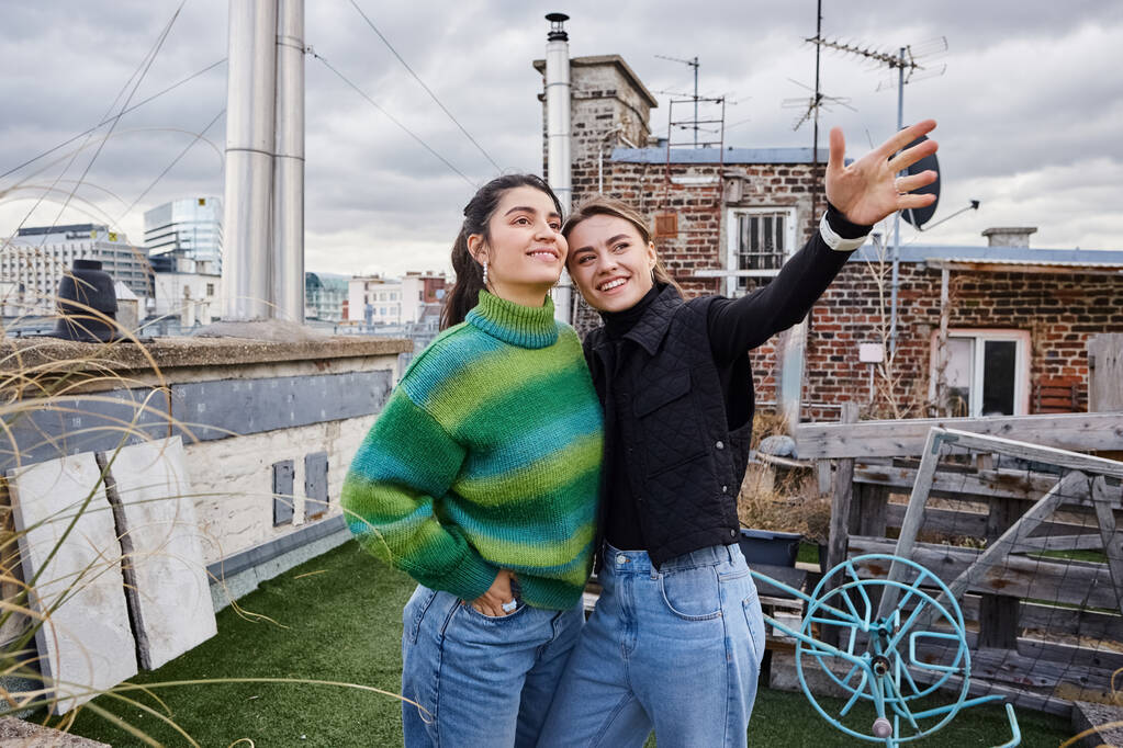 felice giovane coppia lesbica in abbigliamento casual in piedi insieme del tetto e guardando la vista sulla città - Foto, immagini