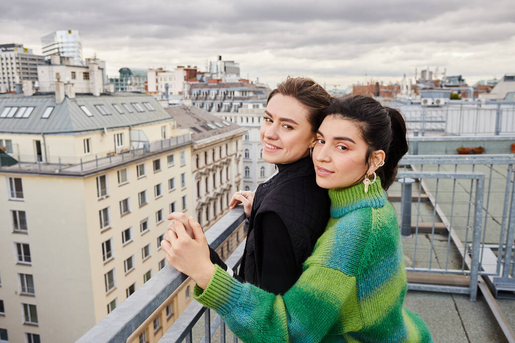 Young lgbt couple in casual attire looking at city on rooftop, a moment of love and connection - Photo, Image