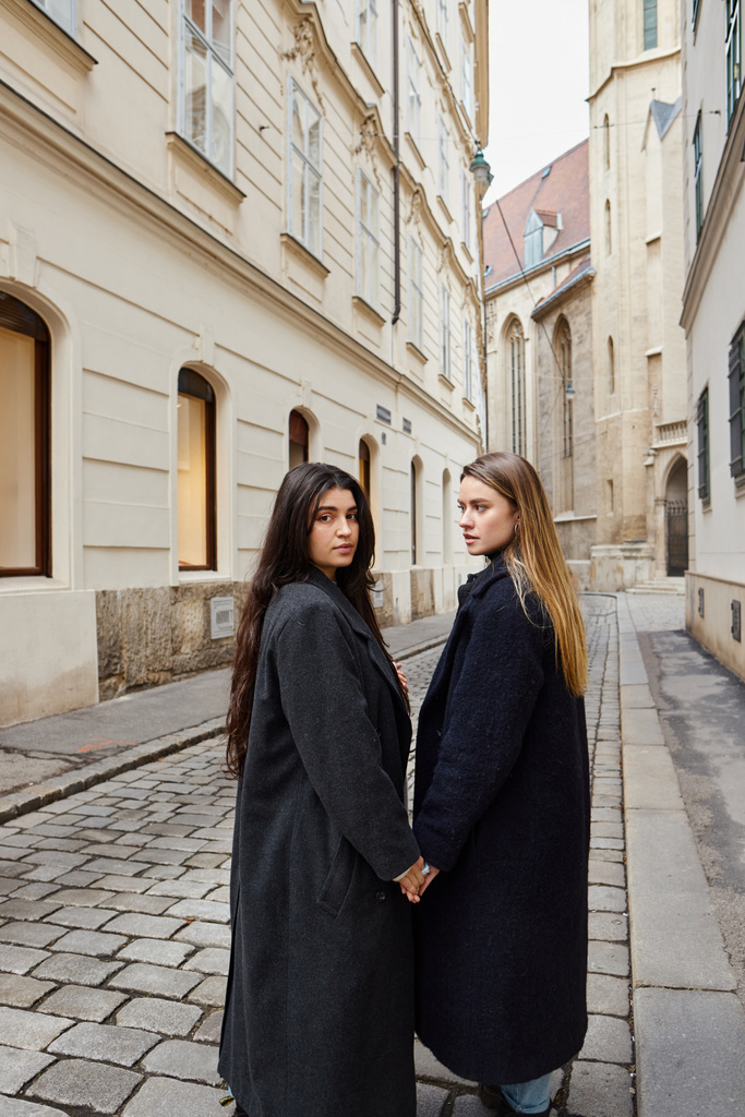 幸せな若いレズビアンカップルでトレンディなアウターウェアを保持しながら,ヨーロッパの都市を歩いています, lgbt - 写真・画像