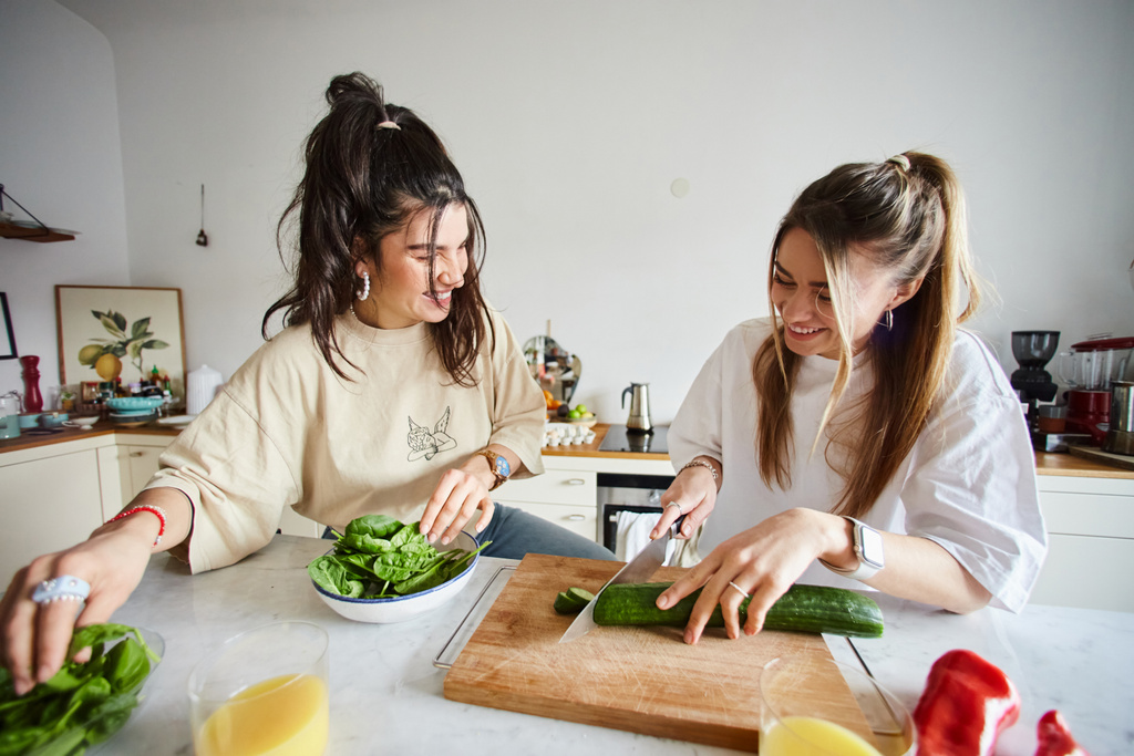 веселые молодые девушки улыбаются, делая салат вместе на современной кухне, lgbtq концепции - Фото, изображение