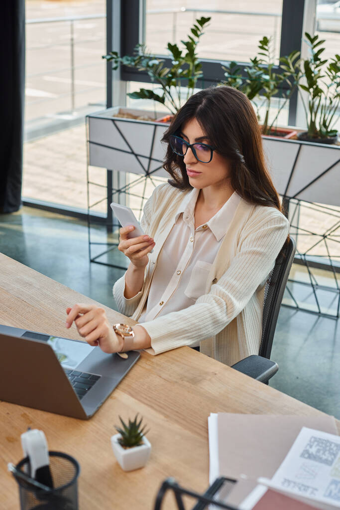 Uma mulher de negócios senta-se a uma mesa em um escritório moderno, usando um laptop para trabalhar em conceitos de franquia. - Foto, Imagem
