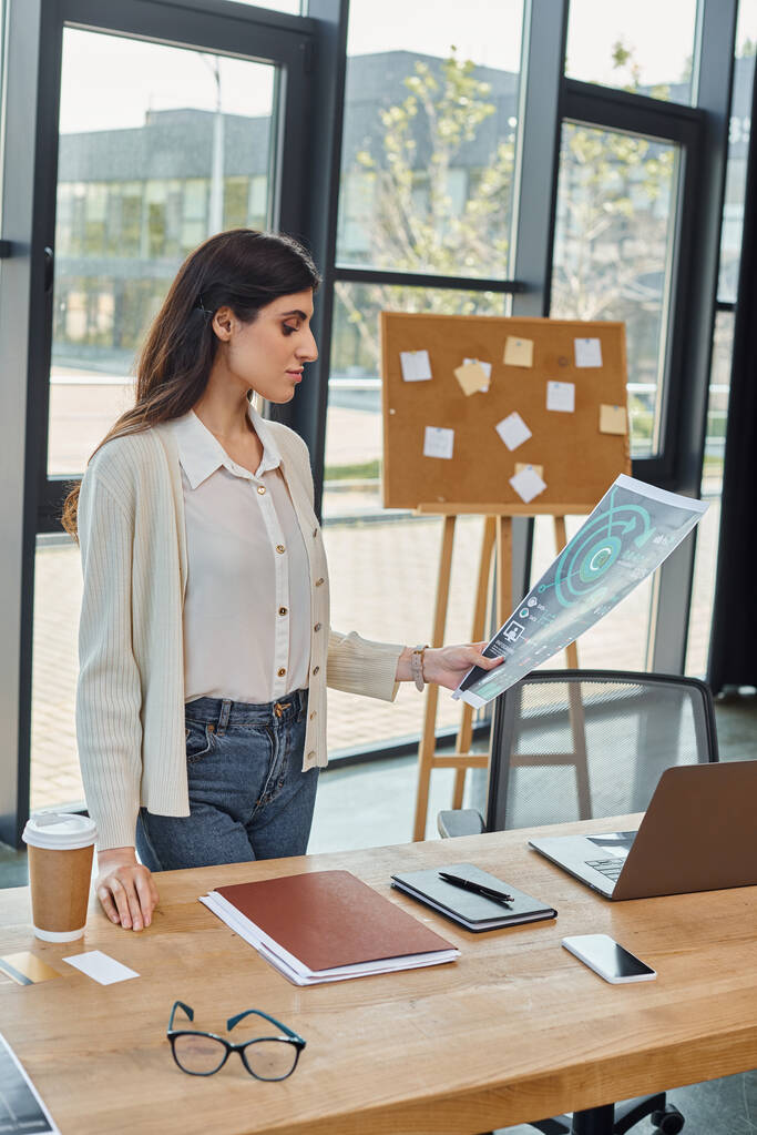 Eine Geschäftsfrau steht in einem modernen Büro und konzentriert sich auf ihre Charts - Foto, Bild