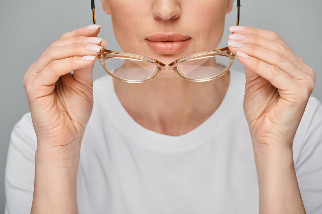 kivágott kilátás nő alkalmi városi öltözékben tartó szemüveg előtte szürke háttér - Fotó, kép