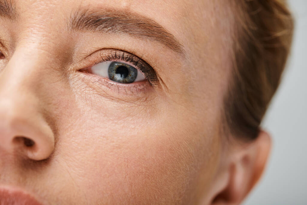 close-up van aantrekkelijke vrouw met blond haar op zoek naar camera met contact lense op haar oog - Foto, afbeelding