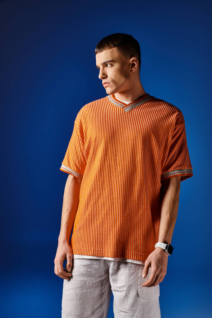 Fashion portrait of handsome man in orange shirt and white shorts posing on blue background - Photo, Image