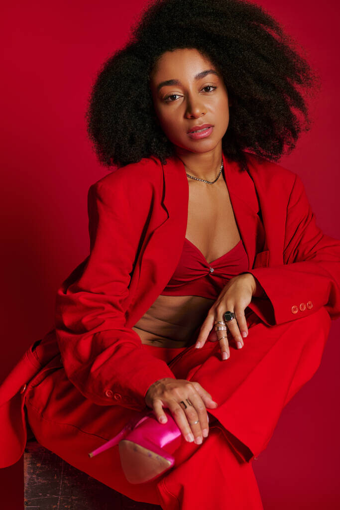 beautiful sexy african american woman in red attire sitting and looking at camera, fashion concept - Photo, Image