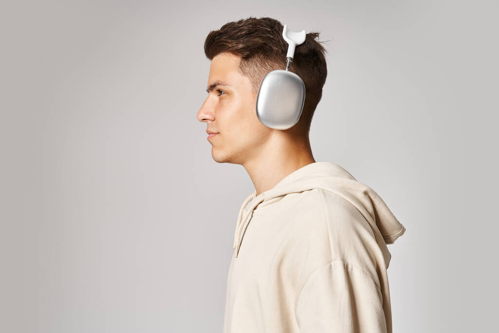 profil sebevědomého mladého muže s hnědými vlasy ve sluchátkách na světlém pozadí - Fotografie, Obrázek