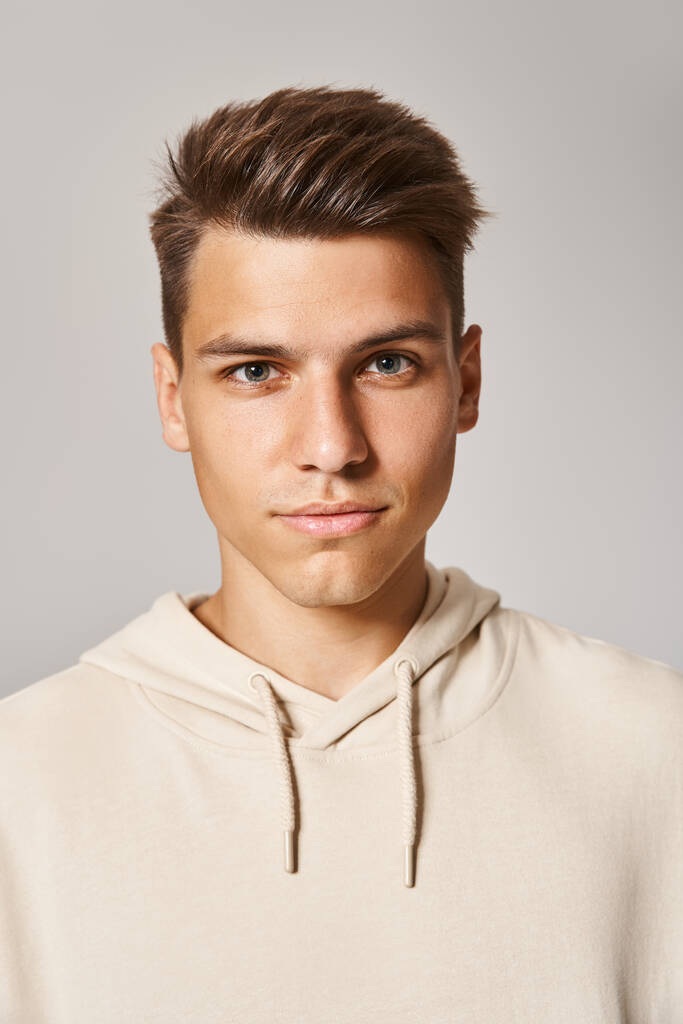 портрет привлекательного молодого человека с каштановыми волосами и серыми глазами на светлом фоне - Фото, изображение