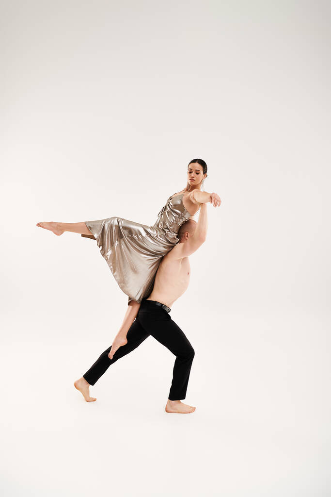 Shirtless joven hombre y mujer en vestido brillante ejecutando movimientos acrobáticos de baile sobre fondo blanco - Foto, Imagen