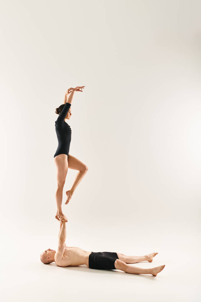 Un joven sin camisa y una mujer en una pose de baile, mostrando su flexibilidad haciendo divisiones en un entorno de estudio sobre un fondo blanco. - Foto, imagen
