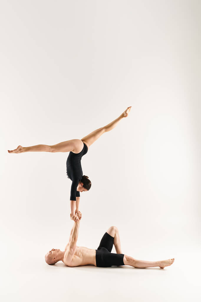 A shirtless young man and a young woman gracefully performing a handstand together in a studio setting against a white background. - Photo, Image