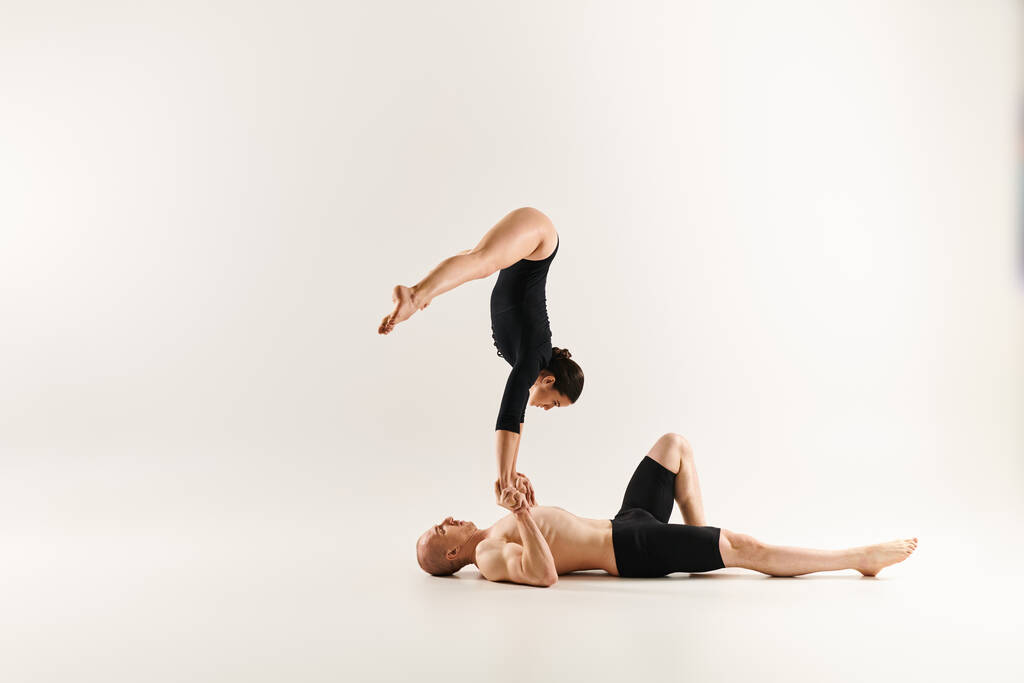 Hemdloser Mann balanciert im Handstand auf einem anderen Mann und zeigt Stärke und Geschick in der Akrobatik, weißer Studiohintergrund. - Foto, Bild